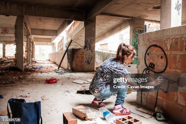 woman spraying graffiti on building wall - sprayer graffiti stock-fotos und bilder