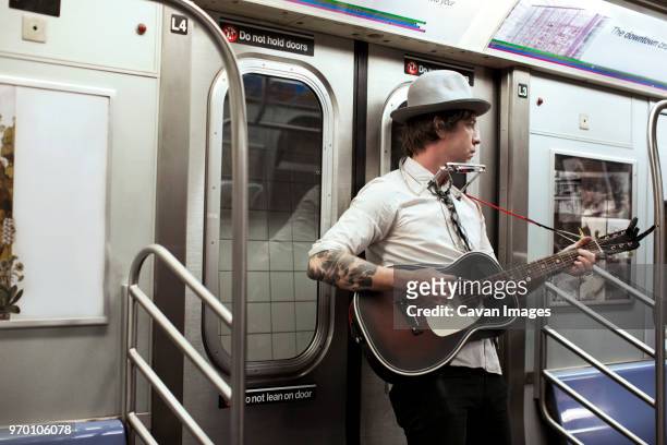 street musician playing guitar in subway train - street performer stock pictures, royalty-free photos & images