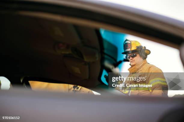 firefighter looking away while standing by car - carro de bombeiro fotografías e imágenes de stock