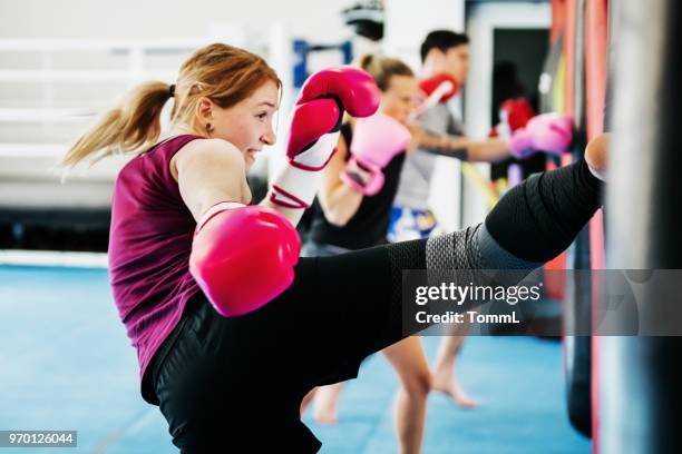 gruppe von frauen kickboxen gemeinsam in der turnhalle - boxing training stock-fotos und bilder