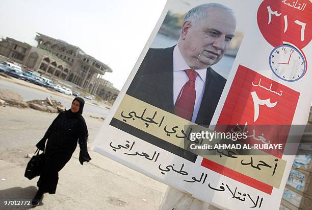 An Iraqi woman walks past an election campaign poster bearing a picture of Shiite deputy prime minister Ahmed Chalabi in Baghdad on February 24,...