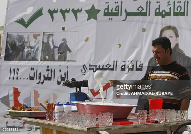 An Iraqi man sells sweets in front of an election campaign billboard of the broad Al-Iraqiya secular alliance in downtown Baghdad on February 24,...