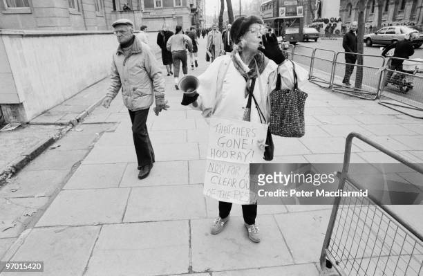Protestor with a town-crier's bell and a placard reading 'Thatcher's Gone! Hooray! Now For A Clear Out Of The Rest!', in London on the day of...