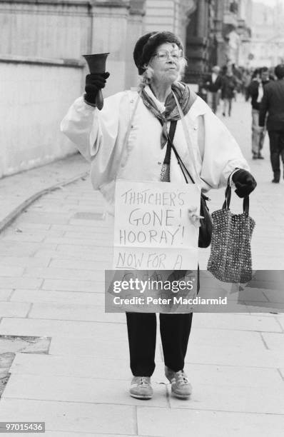 Protestor with a town-crier's bell and a placard reading 'Thatcher's Gone! Hooray! Now For A Clear Out Of The Rest!', in London on the day of...