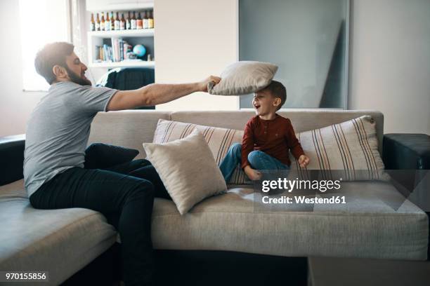 father and little son playing together on the couch in the living room - rough housing stock pictures, royalty-free photos & images