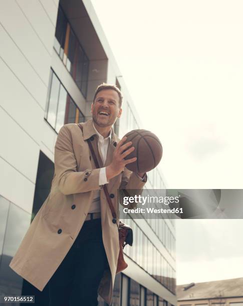 happy businessman playing basketball outside office building - german film ball 2018 stock-fotos und bilder