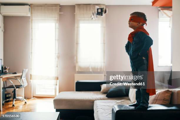 little boy dressed up as a superhero standing on coffee table at home - cape bildbanksfoton och bilder