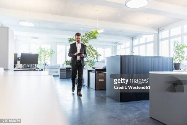 businessman walking in office, using digital tablet - green suit foto e immagini stock