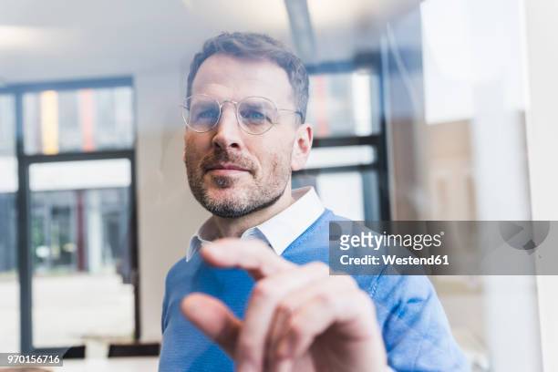 confident businessman touching glass pane - portrait concentration stock pictures, royalty-free photos & images