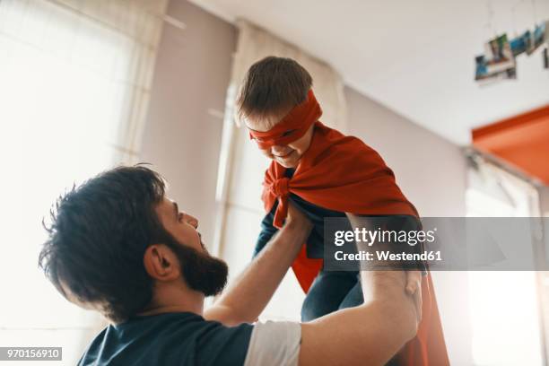 father playing with his little son dressed up as a superhero - genderblend stock-fotos und bilder