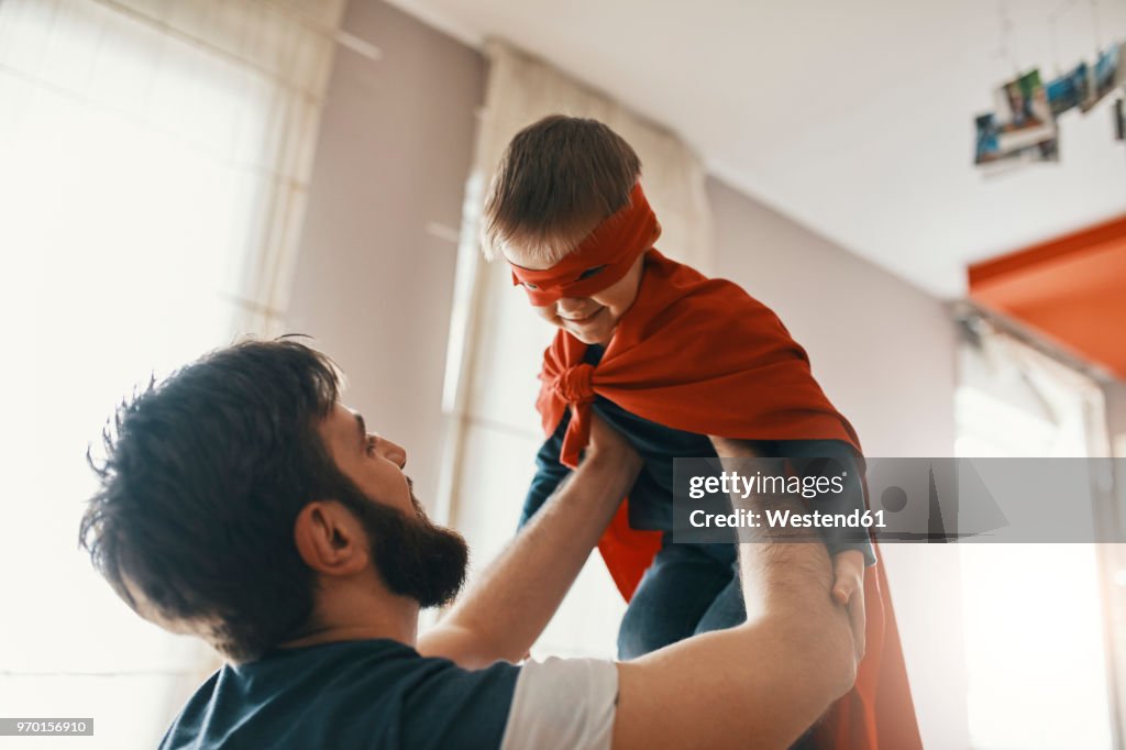 Father playing with his little son dressed up as a superhero