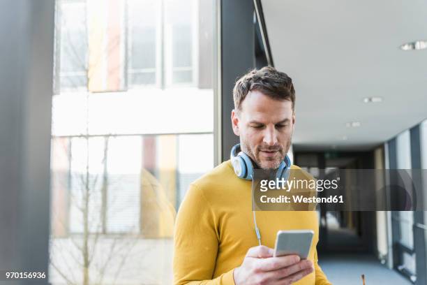 casual businessman in office using smartphone - yellow stock-fotos und bilder