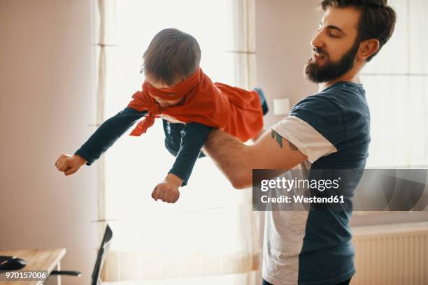father playing with his little son dressed up as a superhero - superhero dad stock pictures, royalty-free photos & images