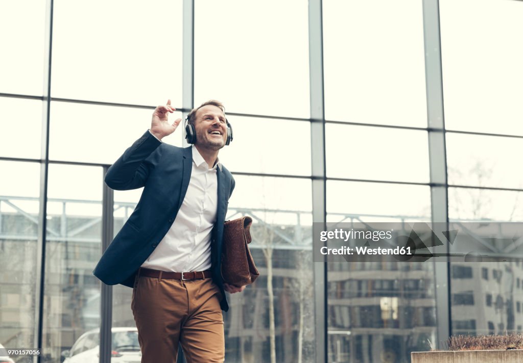 Happy businessman listening to music with headphones