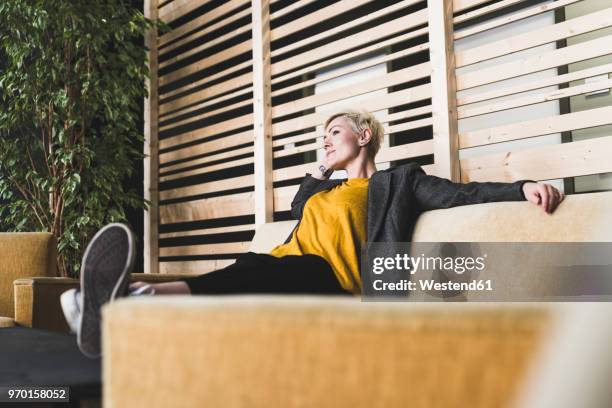 casual businesswoman sitting on couch in lounge - businesswoman couch fotografías e imágenes de stock