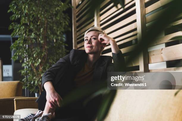 casual businesswoman sitting on couch in lounge - businesswoman couch stock pictures, royalty-free photos & images