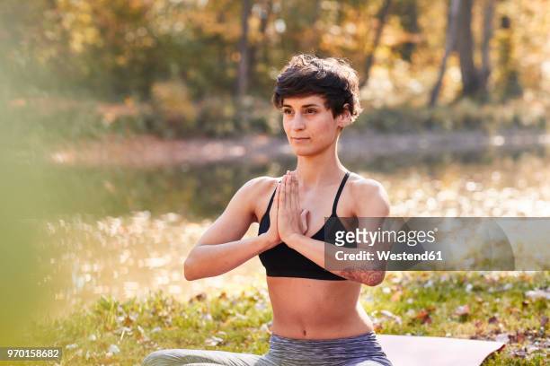 mid adult woman in forest practicing yoga, meditation - schwarzes haar stock-fotos und bilder