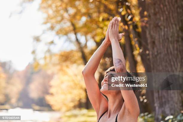 smiling mid adult woman in forest practicing yoga - munich autumn stock pictures, royalty-free photos & images