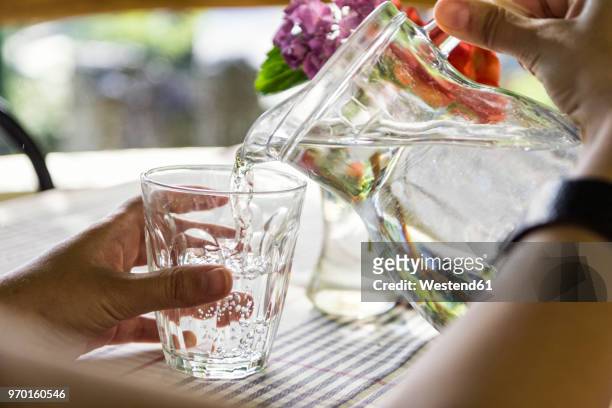 woman's hands pouring water into glass, close-up - karaffin bildbanksfoton och bilder