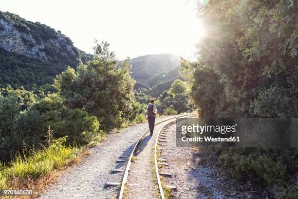 greece, pilion, milies, back view of man walking along rails of narrow gauge railway - pelion fotografías e imágenes de stock