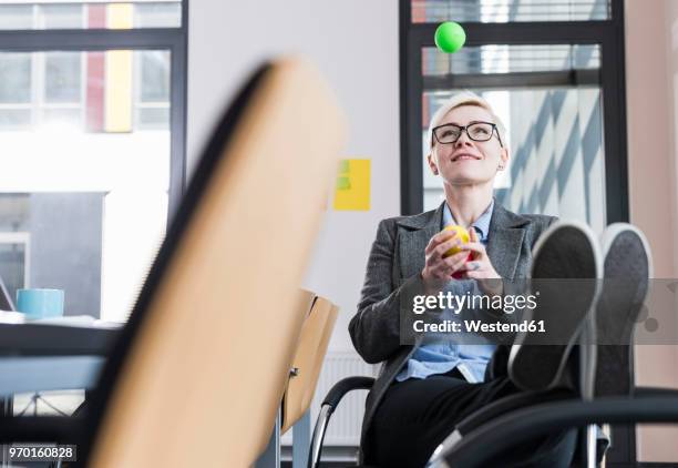 smiling businesswoman juggling with balls in office - jonglieren stock-fotos und bilder