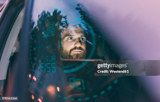 Focused man in car at night surrounded by dashboard projection