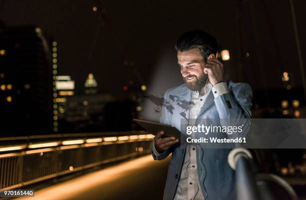 young man on bridge at night with world map emerging from tablet - break through fotografías e imágenes de stock