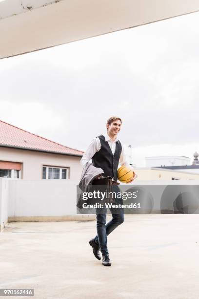 smiling businessman with basketball walking at parking garage - german film ball 2018 stock-fotos und bilder