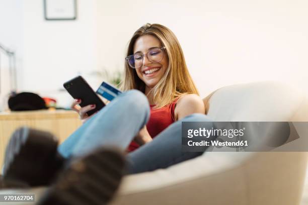 happy young woman using smartphone and credit card in the office - online bank service stock pictures, royalty-free photos & images