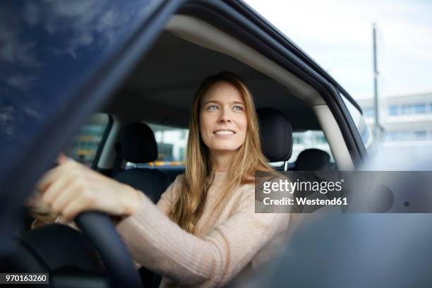 portrait of smiling young woman sitting in car - vehicle door stock pictures, royalty-free photos & images