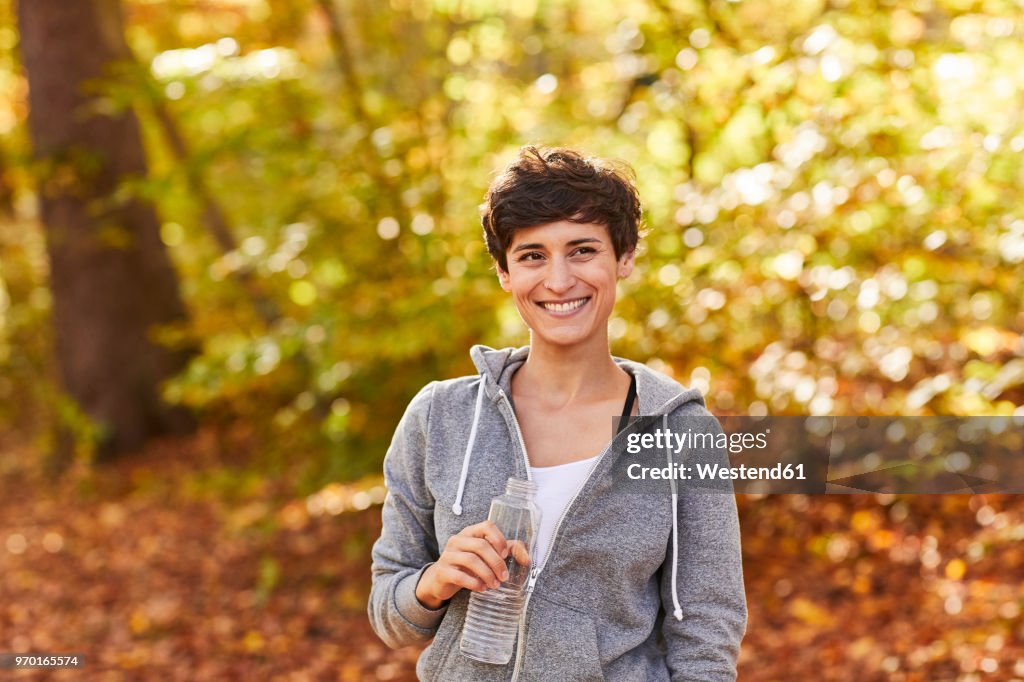 Smiling female jogger with water bottle