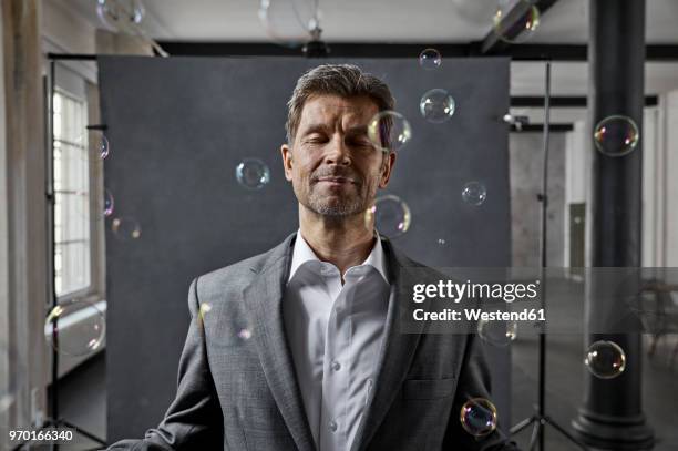 portrait of mature businessman with bubbles in front of black backdrop in loft - surrounding ストックフォトと画像