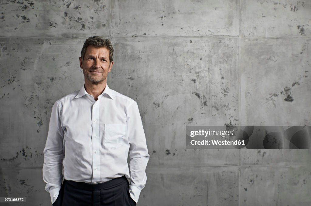 Portrait of smiling mature man in front of concrete wall