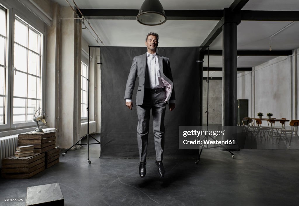 Mature businessman floating in front of black backdrop in loft