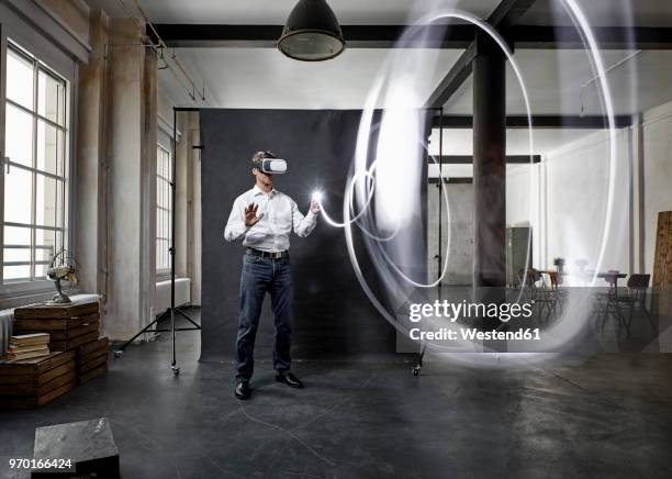 mature man with vr glasses light painting in front of black backdrop in loft - virtual reality glasses stock-fotos und bilder