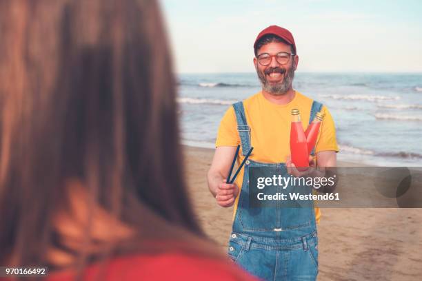 happy man in dungarees on the beach offering soft drink to woman - couple portrait soft stock pictures, royalty-free photos & images