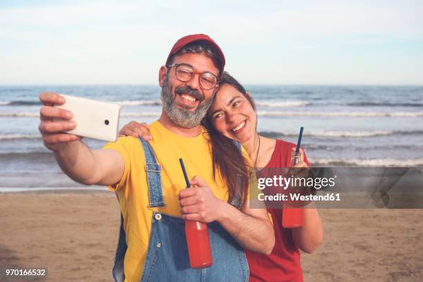 couple with soft drinks taking selfie with smartphone on the beach - couple portrait soft ストックフォトと画像