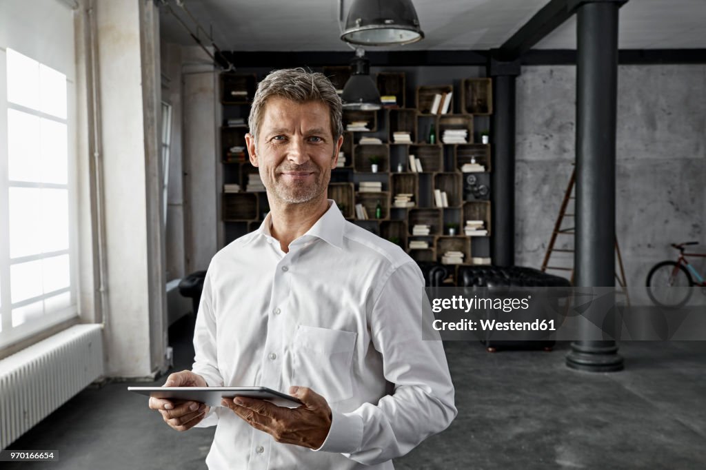 Portrait of mature man using digital tablet in loft flat
