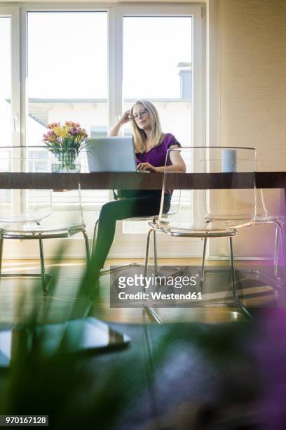 businesswoman sitting at meeting table looking at laptop - tisch betrachten stock-fotos und bilder