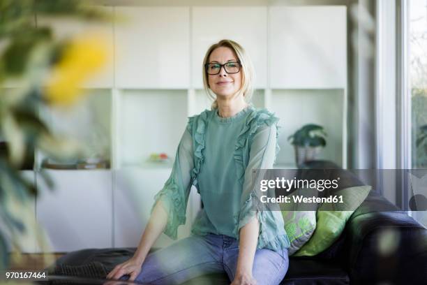 portrait of content businesswoman sitting on couch - stolz stock-fotos und bilder