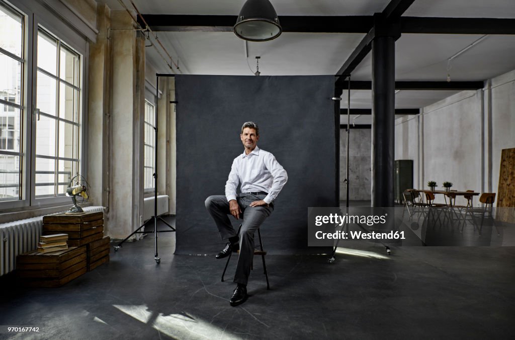 Portrait of mature businessman in front of black backdrop in loft