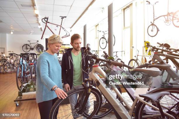 salesman helping customer with e-bike - electric bike stockfoto's en -beelden