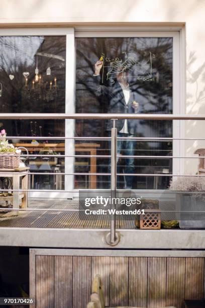 senior businessman drawing formula on his patio door - home economics ストックフォトと画像