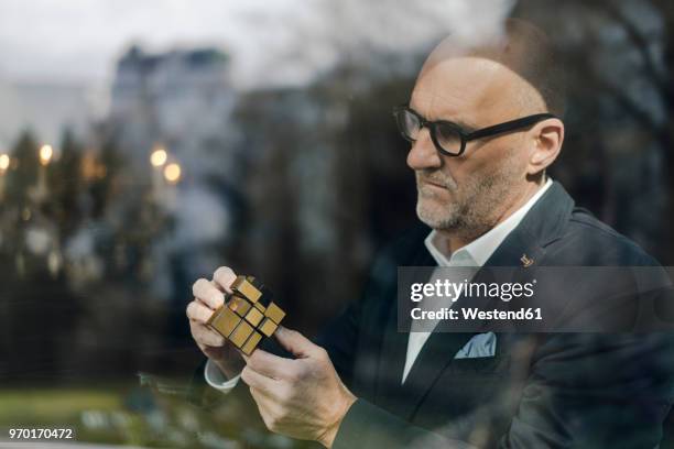 senior businessman putting together puzzle cube - 2018 futures game stock pictures, royalty-free photos & images