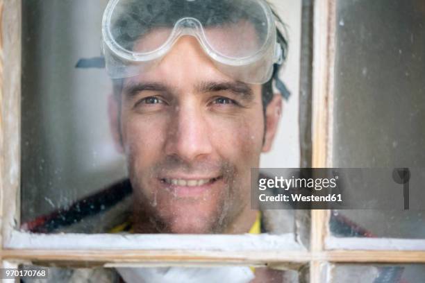 portrait of a handyman , renovating flat, looking through window - handyman smiling stock pictures, royalty-free photos & images