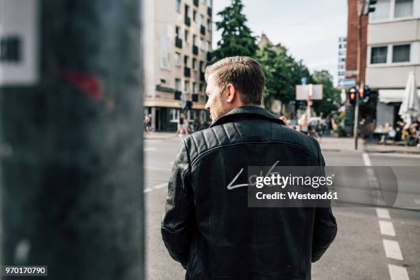 back view of young man wearing black leather jacket with writing 'love' - giacca di pelle foto e immagini stock