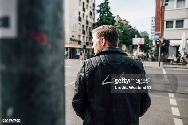 back view of young man wearing black leather jacket with writing 'love' - jacket stock pictures, royalty-free photos & images