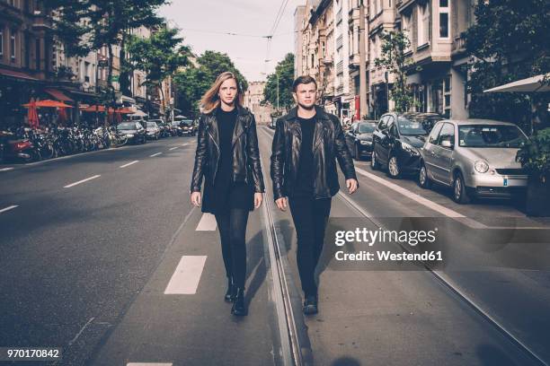 young couple wearing black matching clothes walking side by side on the street - nebeneinander-stehen stock-fotos und bilder