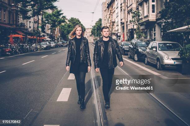 young couple wearing black matching clothes walking side by side on the street - matching outfits stock pictures, royalty-free photos & images