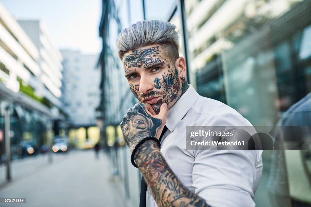 Young businessman with tattooed face walking in the city, portrait